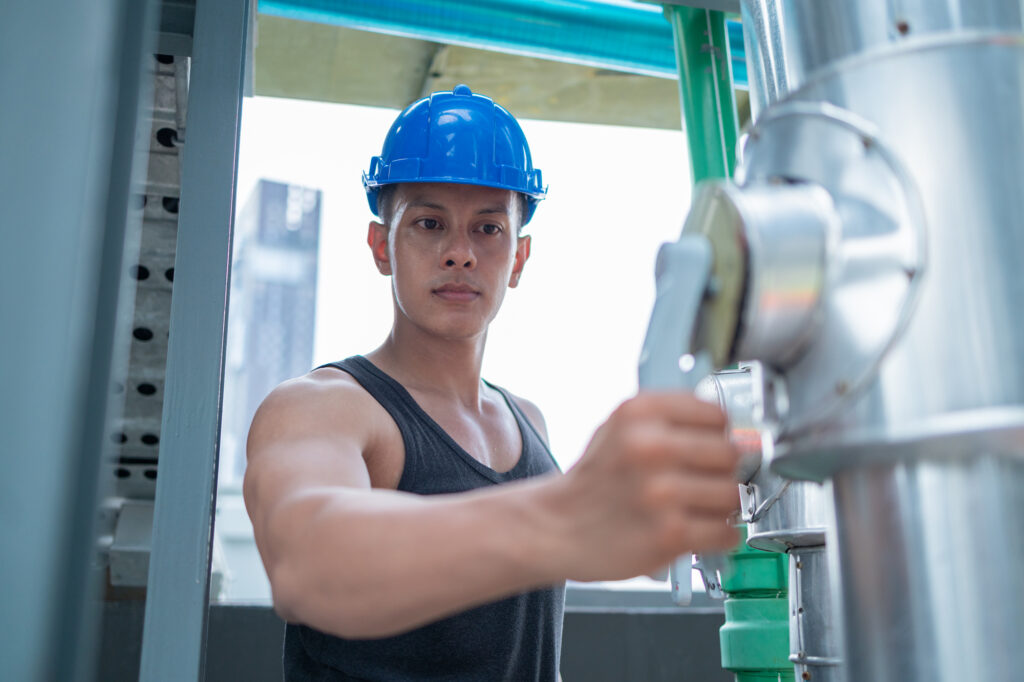 Worker Adjusting Valves at Industrial Pipeline